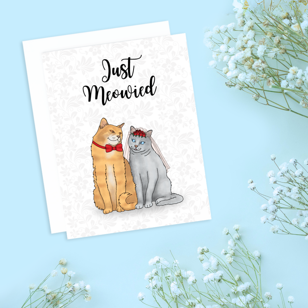 A photo of a wedding card. It has two cats in wedding garb. Text reads, Just Meowied.