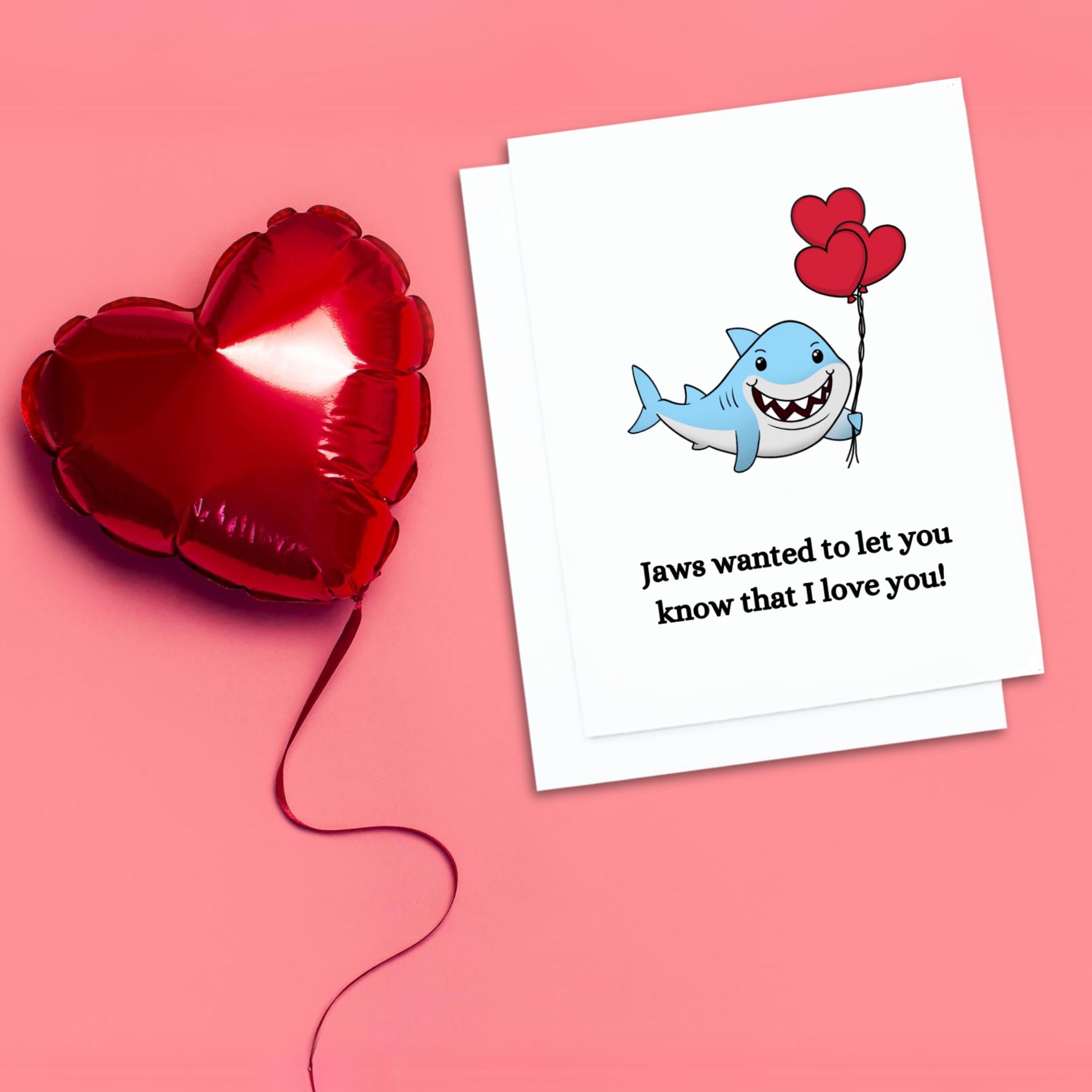 Valentines card. A smiling shark holding red balloons. text reads, Jaws wanted to let you know that I love you.