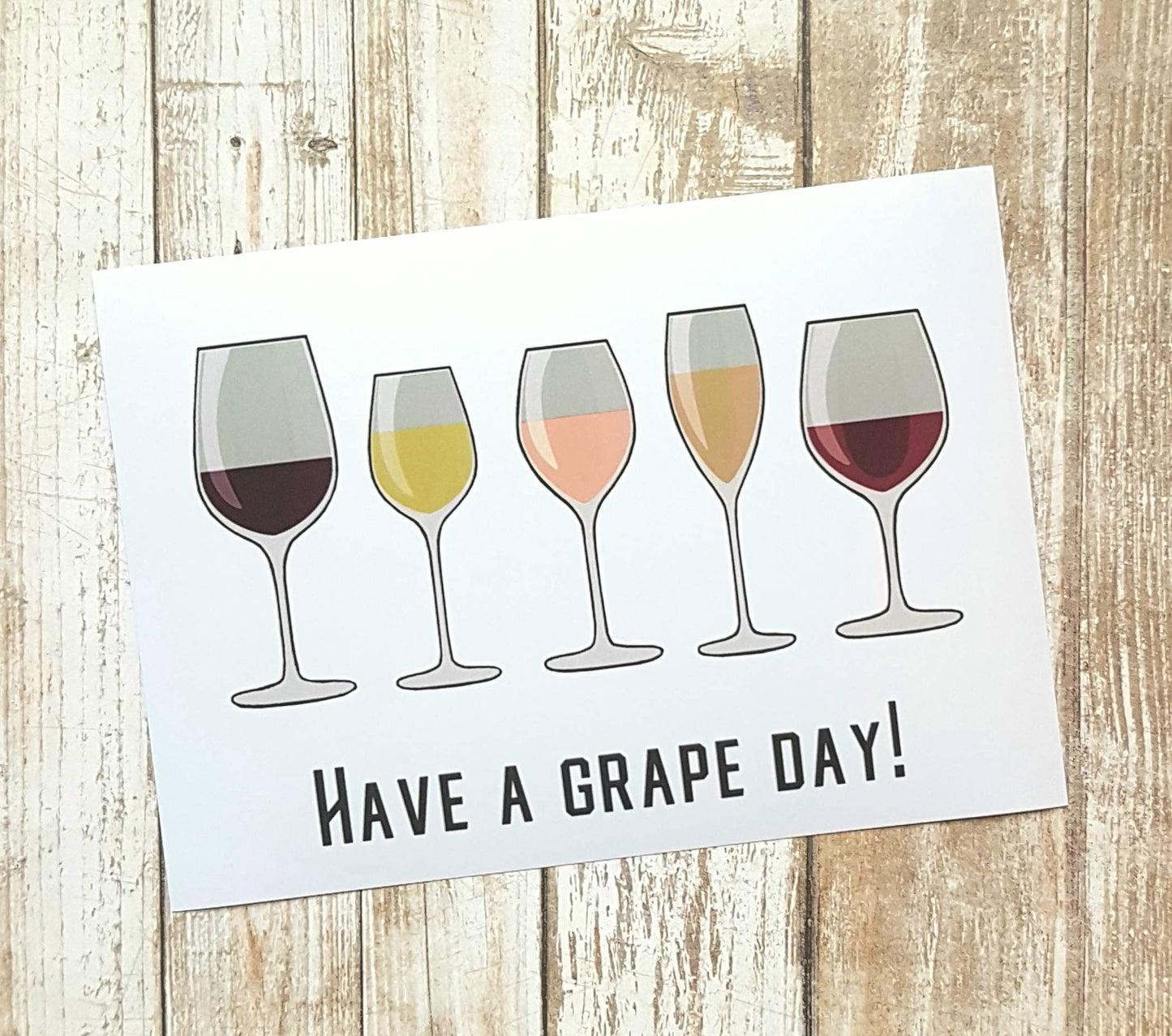A photo of a print. It has wine glasses on it. Text reads, Have a Grape Day!